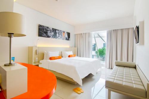 a hotel room with a white bed and a chair at HARRIS Hotel and Conventions Denpasar Bali in Denpasar
