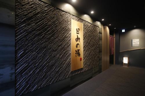 a wall with a sign on the side of a building at Dormy Inn Miyazaki Natural Hot Spring in Miyazaki