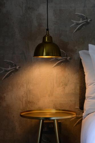 a pendant light hanging over a table next to a bed at The Litton in Litton
