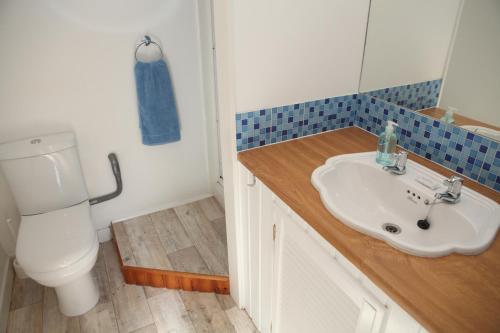 Harbour Cottage في سترومنيس: حمام مع حوض أبيض ومرحاض