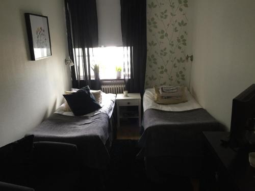 a small room with two beds and a window at Höjdens Lågprishotell in Mönsterås