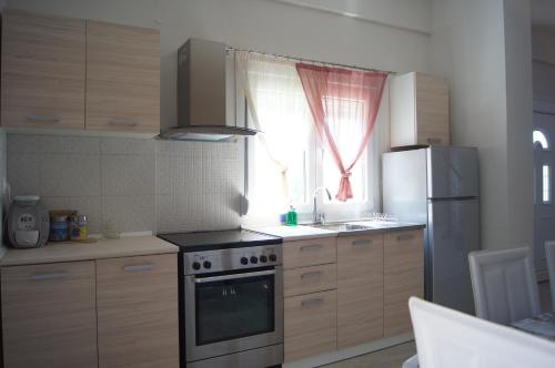 a kitchen with a stove and a refrigerator and a window at Terra Kotta in Paralia Vrachou