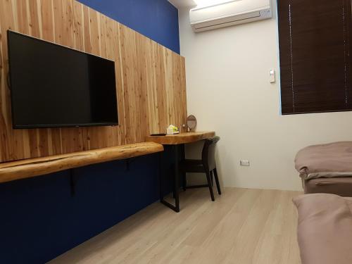 a room with a tv on a wall with a table at Romeo B&B in Taitung City