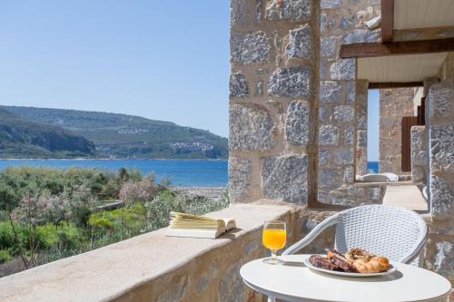 een tafel met een bord eten en een glas wijn bij Porto Vitilo Boutique Hotel in Karavostasion