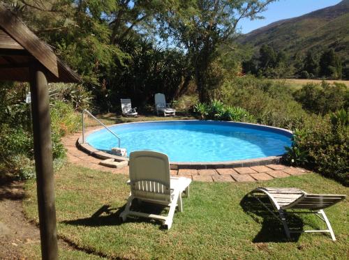 a swimming pool with a chair and a table and a chair at Frog Mountain Getaway in Swellendam