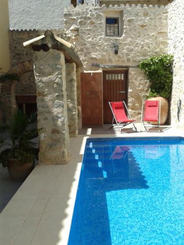 a swimming pool with two chairs and a house at Casa Sastre Segui in Patró