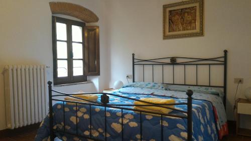a bedroom with a bed with a blue comforter and a window at Villa La Nussa in Capolona