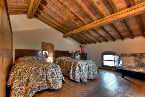 two beds in a room with wooden ceilings at Agriturismo il Prato in Palaia