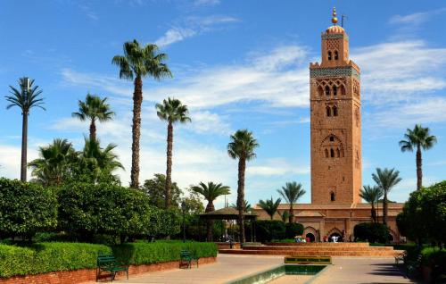 a clock tower with palm trees in front of a building at Appartement Wassim - Gueliz in Marrakech