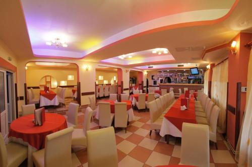 restauracja z czerwono-białymi stołami i krzesłami w obiekcie Hotel Martisorul w mieście Kaczyka