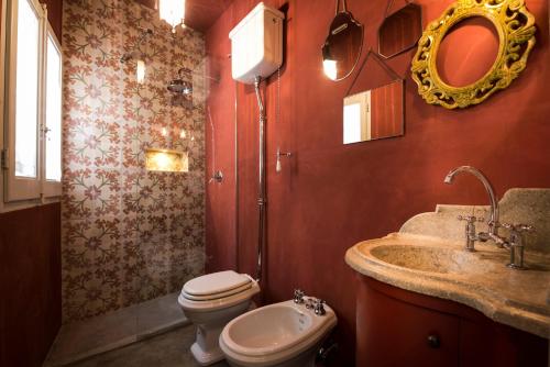 a bathroom with a toilet and a sink and a mirror at Sanbartolomeo Casa & Putìa in Scicli