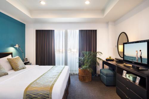um quarto de hotel com uma cama e uma televisão de ecrã plano em Somerset Vientiane em Vientiane
