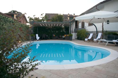 a swimming pool in a yard with chairs and an umbrella at Cascina36 B&B in Pregnana Milanese