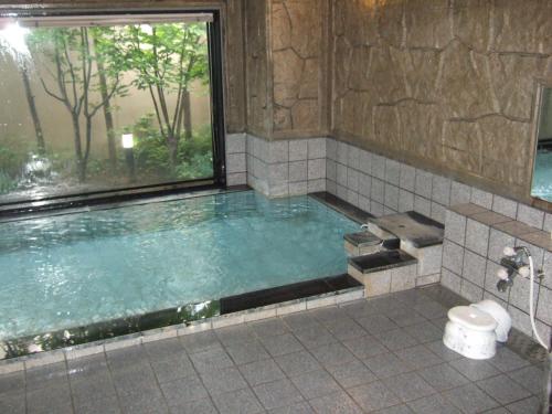 a large tub with a window in a bathroom at Hotel Route-Inn Itoigawa in Itoigawa