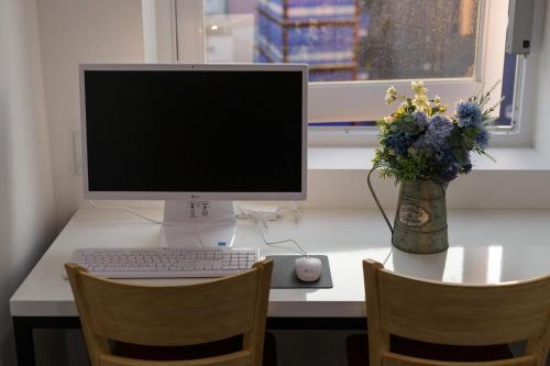 einen Schreibtisch mit einem Computer und einer Blumenvase in der Unterkunft Myeongdong Sunshine Guesthouse in Seoul