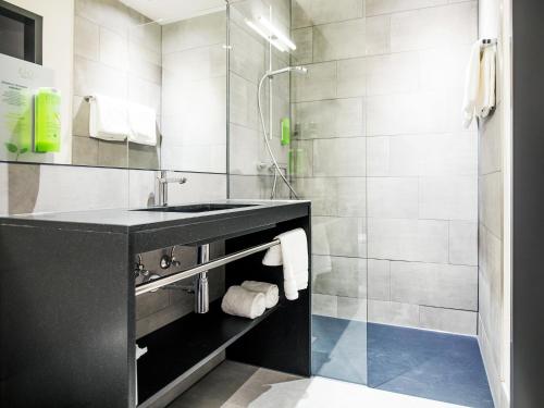 a bathroom with a sink and a shower at RiKu HOTEL Ulm in Ulm