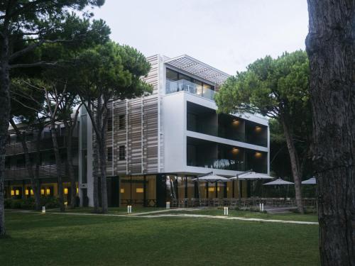 un edificio bianco con alberi di fronte di Hotel Mediterraneo Suite&Residence a Lido di Jesolo