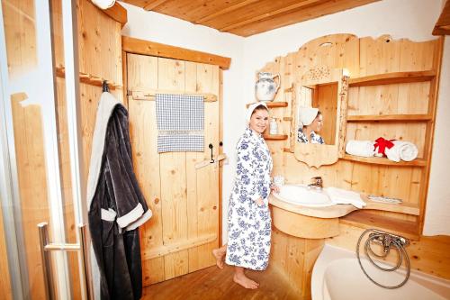 een vrouw in een badkamer met een wastafel bij Im Dörfl Anno 1873 in Irdning