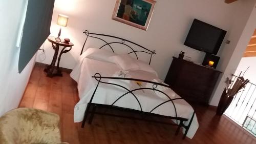 a bedroom with a bed with white sheets and a tv at Villa Posta Vecchia in Loreo