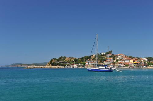 a sail boat in the water with a town in the background at Hotel Korakakis Beach in Finikounta