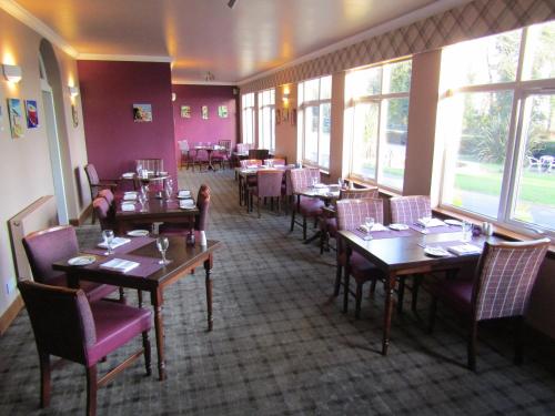 a dining room with tables and chairs and windows at Kingswood Hotel in Burntisland