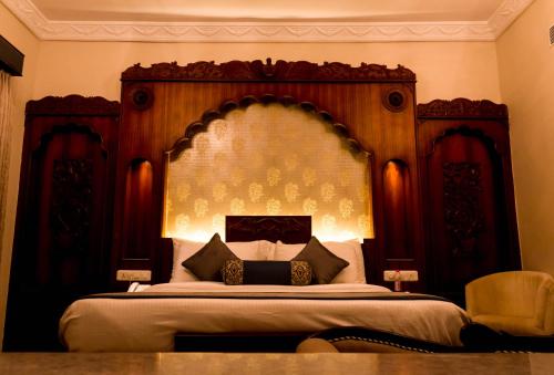 a bedroom with a large bed with a wooden headboard at Pratap Mahal Pushkar IHCL SeleQtion in Pushkar