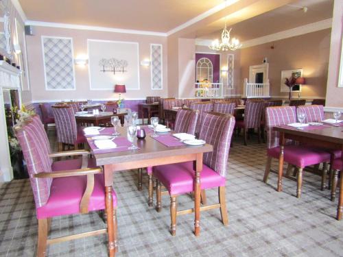 a restaurant with wooden tables and pink chairs at Kingswood Hotel in Burntisland