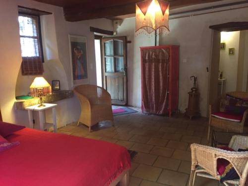 Schlafzimmer mit einem roten Bett, einem Tisch und Stühlen in der Unterkunft Mas des Nabières in Saint-Martial