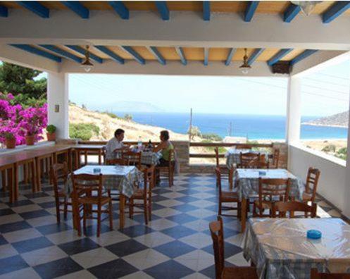 two people sitting at a restaurant with tables and chairs at Koukos in Agia Theodoti