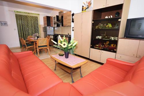 sala de estar con sofá rojo y mesa con flores en Apartments Bijuk, en Sukošan