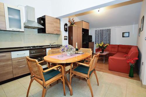 cocina y comedor con mesa y sofá rojo en Apartments Bijuk, en Sukošan