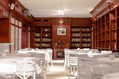 a dining room with white tables and chairs and bookshelves at Hotel Bryza Resort & Spa in Jurata