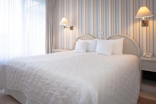a bedroom with a white bed with white pillows at Hotel Bryza Resort & Spa in Jurata