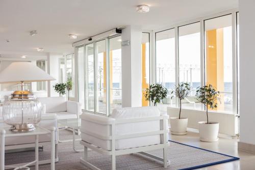 a living room with white furniture and windows at Hotel Bryza Resort & Spa in Jurata