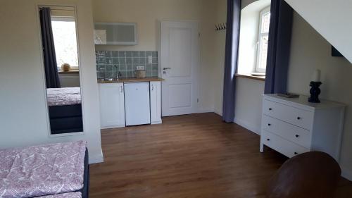 a kitchen with white cabinets and a sink in a room at Pension am Birkensee in Detern