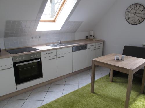 eine Küche mit einem Tisch und einer Uhr an der Wand in der Unterkunft Ferienwohnung Ostseenähe in Hirschburg