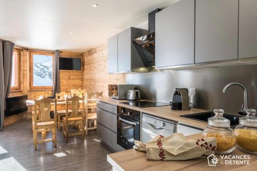 a kitchen with stainless steel appliances and a table at Nazca C8 in Val Thorens