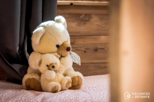 two stuffed teddy bears sitting on a bed at Nazca C8 in Val Thorens