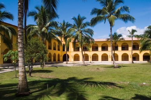サンタ・フェ・デ・アンティオキアにあるHotel y Spa Santa Fe Colonialのヤシの木が目の前に広がる黄色い建物