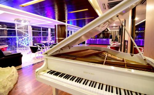 a white piano in a room with a bar at Hotel Noorjahan Grand in Sylhet