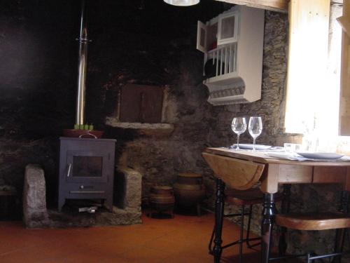 a room with a stove and a table with wine glasses at SaberAmar Little Country in Arouca