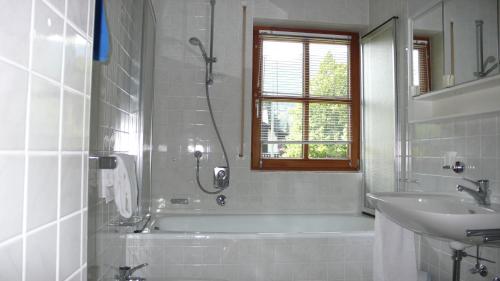 La salle de bains est pourvue d'une baignoire, d'un lavabo et d'une douche. dans l'établissement Apartment Jenny, à Garmisch-Partenkirchen