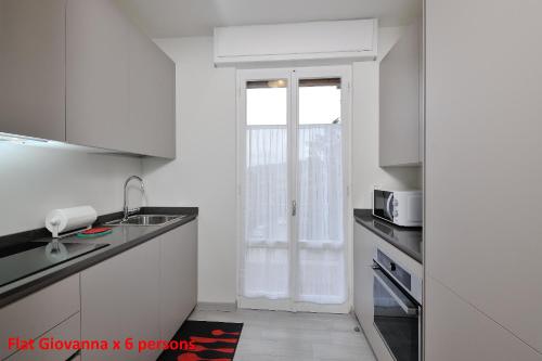 a white kitchen with a sink and a window at Casa Rimidia FLAT GIOVANNA in Perugia