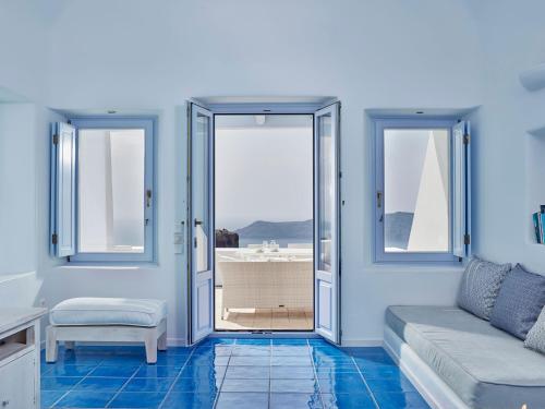 a living room with blue floors and a couch and windows at Astra Suites in Imerovigli