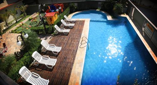 uma vista sobre uma piscina com cadeiras e uma piscina em Hotel Santo Graal em Aparecida