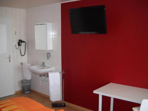 a bathroom with a sink and a red wall at Alpenblick Ferenberg Bern in Stettlen