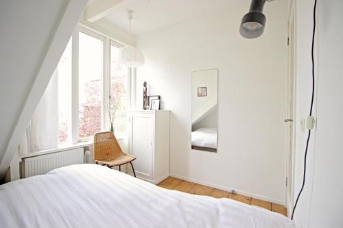 アムステルダムにあるBeautiful 2 floor Vondelpark apartment.のベッドと椅子のある白い寝室