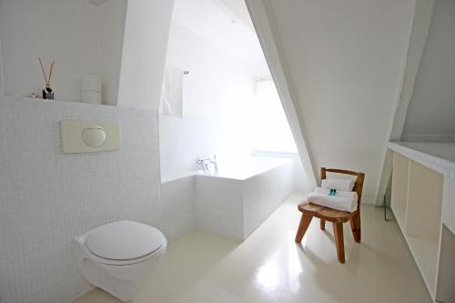 a white bathroom with a toilet and a chair at Beautiful 2 floor Vondelpark apartment. in Amsterdam