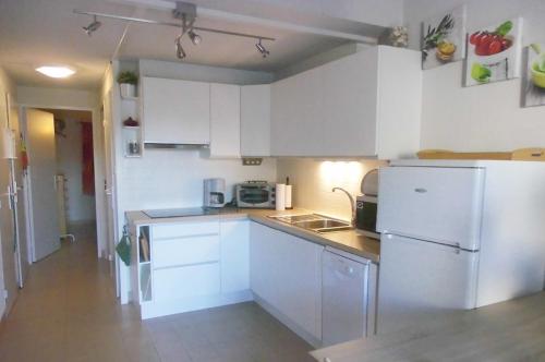 a kitchen with white cabinets and a white refrigerator at Green Village in La Grande-Motte