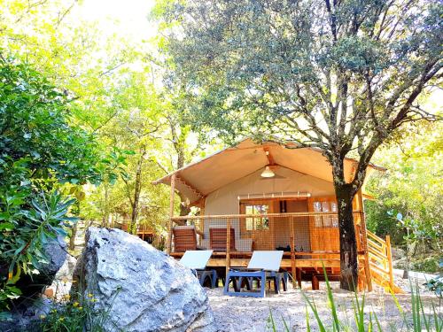 a tent in the woods with a table and chairs at Cabanes Lodges Le Servière in Balazuc